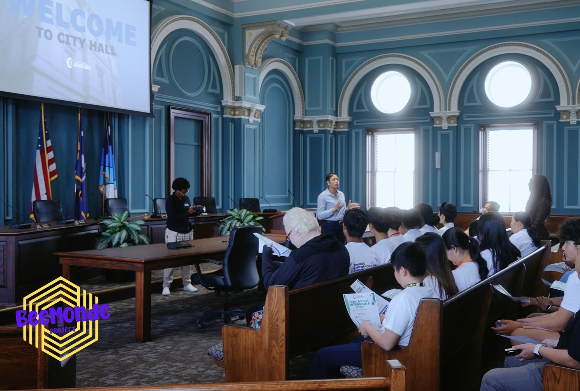 A speaker welcoming students inside a Columbia City Hall meeting room